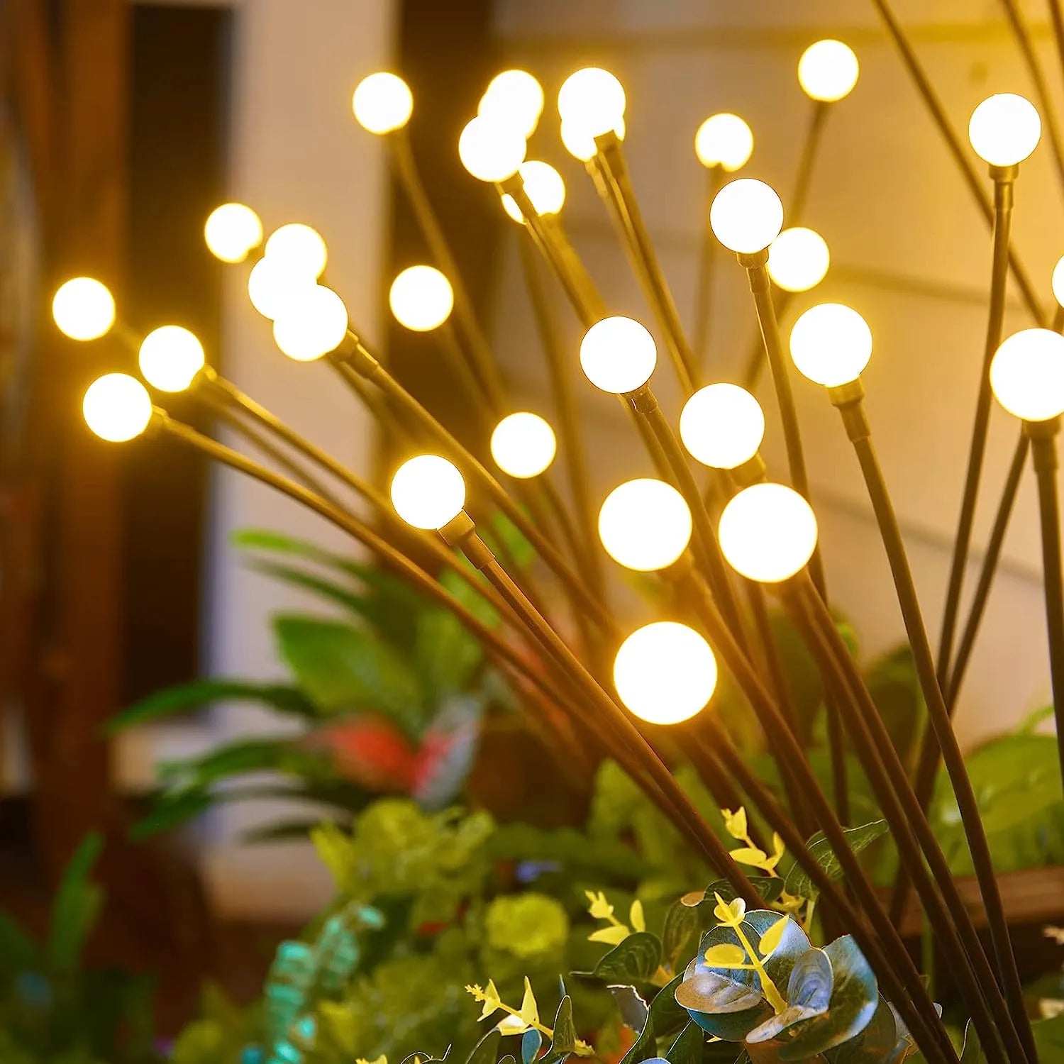 NdotoHuis™ Solar Firefly Lights in an outdoor garden setting, showcasing their warm, firefly-like glow and waterproof design. The lights are staked into the ground and create a magical, inviting atmosphere with multiple lighting modes.