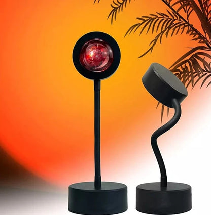 Compact, black USB-powered sunset projector lamp with an adjustable head, casting a mesmerizing blend of red, orange, and pink hues onto a bedroom ceiling.