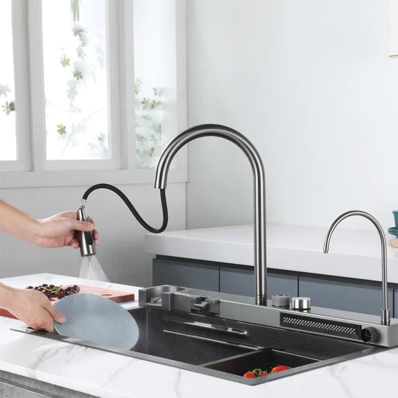 Black stainless steel kitchen sink with waterfall faucet and digital display mounted on a countertop.