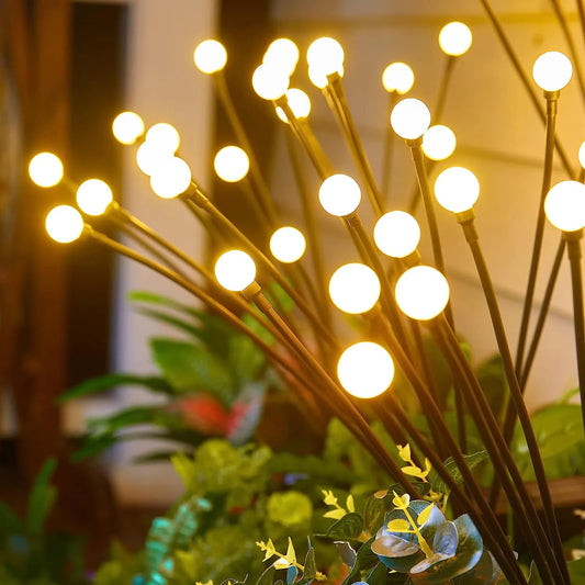 NdotoHuis™ Solar Firefly Lights in an outdoor garden setting, showcasing their warm, firefly-like glow and waterproof design. The lights are staked into the ground and create a magical, inviting atmosphere with multiple lighting modes.